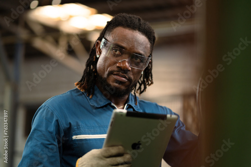 A man with dreadlocks is looking at a drill. The man is wearing a blue shirt and a blue jacket