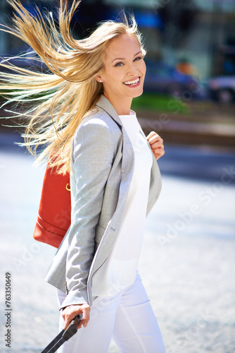 Smile, luggage and businesswoman for urban commute, hair and travel to workplace on street. Portrait, walk and happiness for business consultant in New York, freelance or professional employee