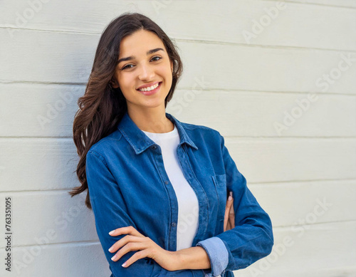smiling young woman brunette casual crossed arms folded student on white wall background
