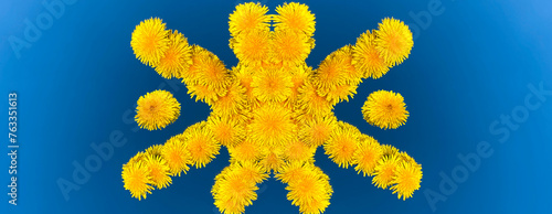 A composition of bright yellow dandelion flowers in the shape of a sun in the center of a blue sky in the background. 