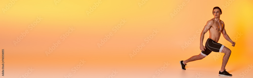 Obraz premium young shirtless man in black shorts exercising actively and looking away on orange backdrop, banner