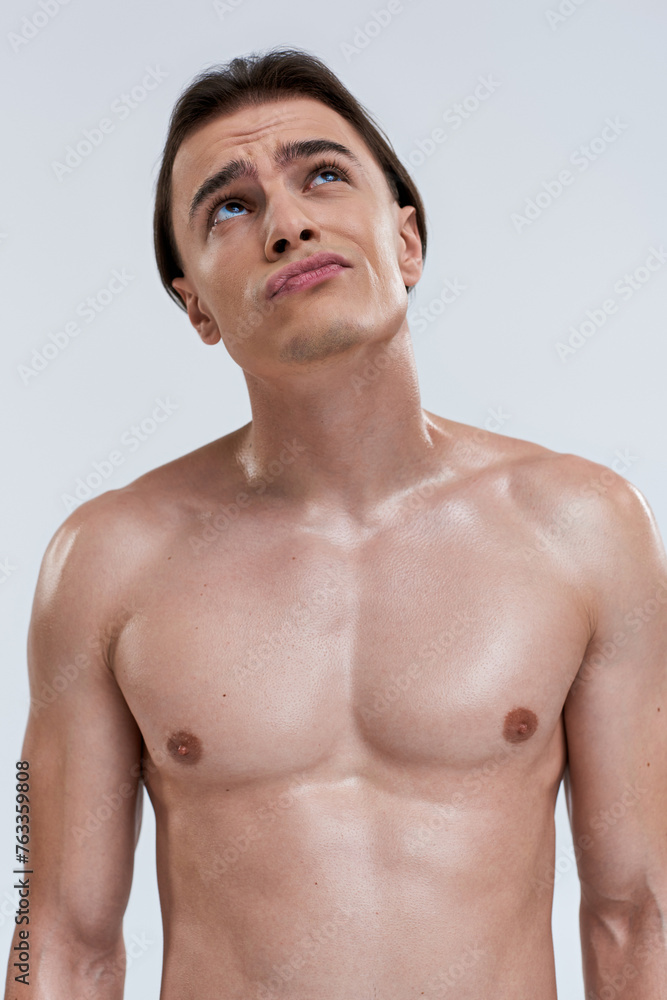 Fototapeta premium concentrated good looking young male model posing topless on gray background and looking away