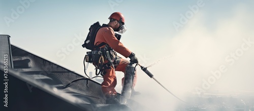 Climber painting chimney on roof, worker spraying water with hose photo
