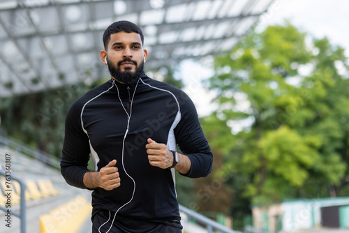 Active bearded man jogging outdoors with headphones
