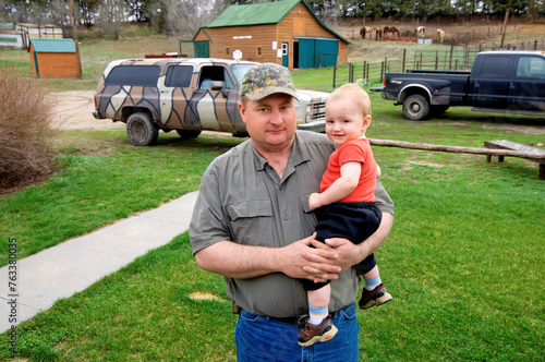 Father holds his young child on a ranch; Gibbon, Nebraska, United States of America photo