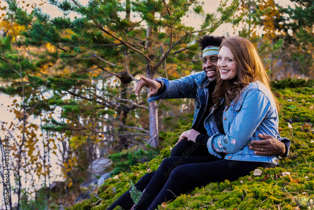 Portrait of a mixed race couple sitting on a grassy hillside enjoying the view, spending quality time together during a fall family outing in a city park; Edmonton, Alberta, Canada Portrait of a mixed race couple sitting on a grassy hillside enjoying the view, spending quality time together during a fall family outing in a city park; Edmonton, Alberta, Canada