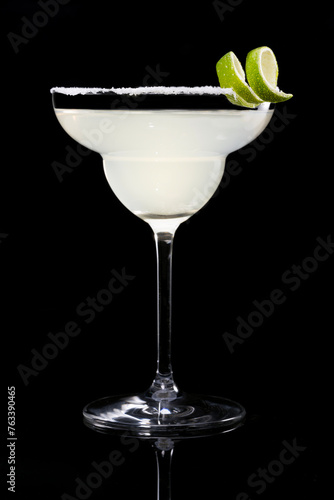 Classic margarita cocktail garnished with lime zest on salt rim, isolated on black reflective surface background