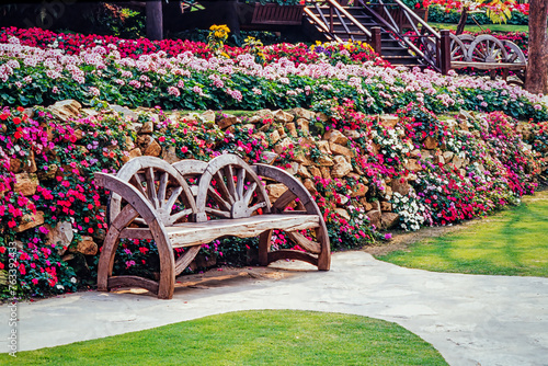 Close-up of a wagon wheel garden bench and flowerbeds; Chiang Rai, Thailand photo