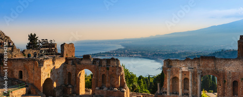 Ruins of a Greek theatre and view of the coastline at sunset in Taormina, Sicily, Italy; Taormina, Sicily, Italy photo