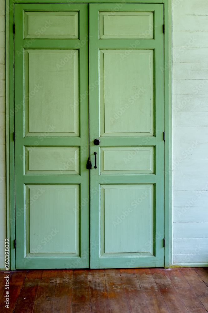 Thai old traditional classic wooden doors with green shutters.