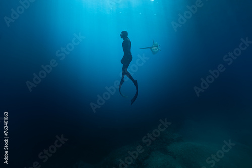 Freediver Swimming in Deep Sea With Sunrays. Young Man Diver Eploring Sea Life. © Lukas Gojda