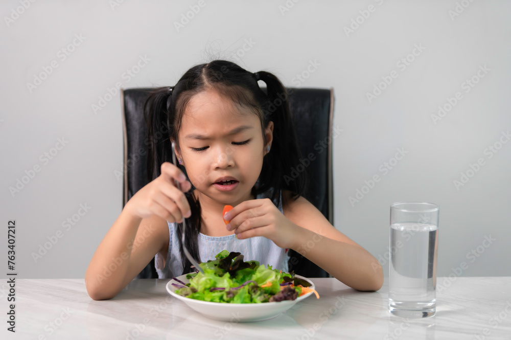 Little asian cute girl refuses to eat healthy vegetables.Nutrition & healthy eating habits for kids concept.Children do not like to eat vegetables. Little asian cute girl refuses to eat healthy vegetables.Nutrition & healthy eating habits for kids concept.Children do not like to eat vegetables.