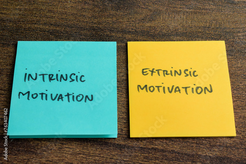 Concept of Intrinsic Motivation or Extrinsic Motivation write on sticky notes isolated on Wooden Table.