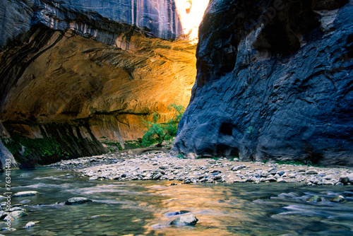 A golden glow emanates from behind a curve in a rock canyon in the Virgin River Narrows, Zion National Park, Utah photo