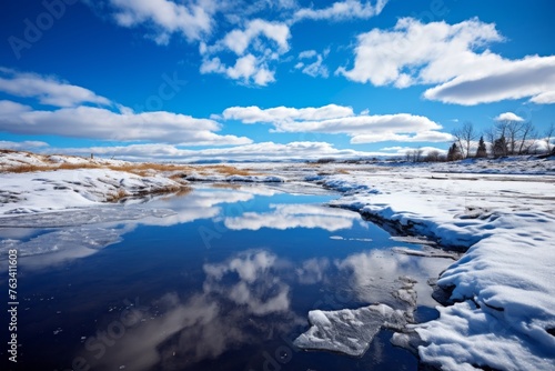 Icy water surface reflecting the winter landscape and blue skies
