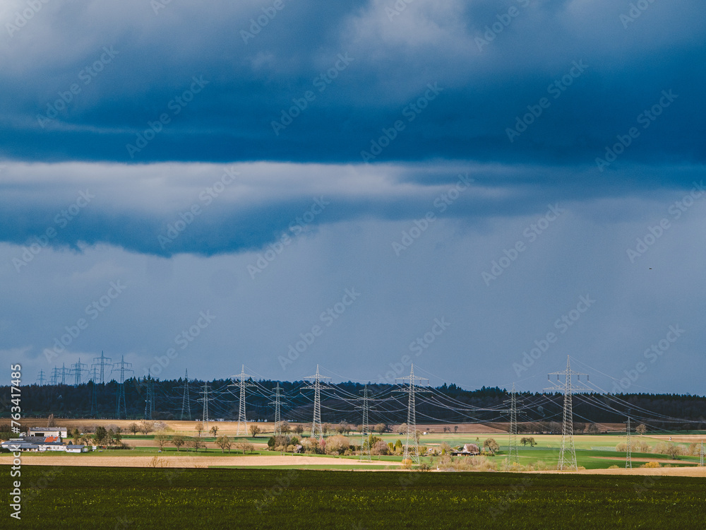 Strommasten einer Überlandleitung und dunkler Wolkenhimmel