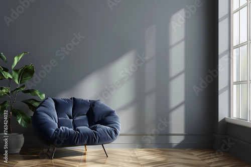 Comfortable dark blue chair near a gray wall in the room, space for text. Soft modern blue armchair near the window in the room and a vase with a plant nearby © Jullia