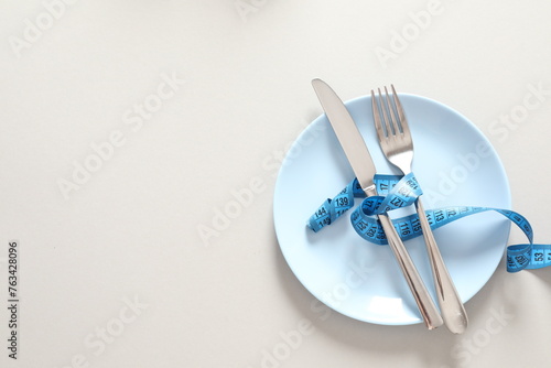 fork and knife with measuring tape on white background 