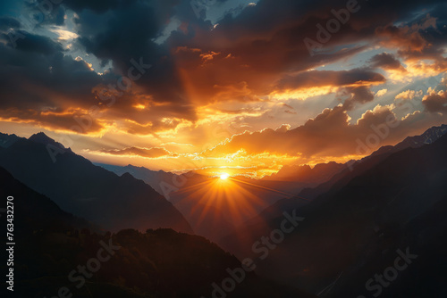 Sunset in mountains. Sun dips behind mountain peaks with golden light. Beautiful nature landscape