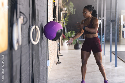 A fit African American strong woman is catching a medicine ball in the gym photo