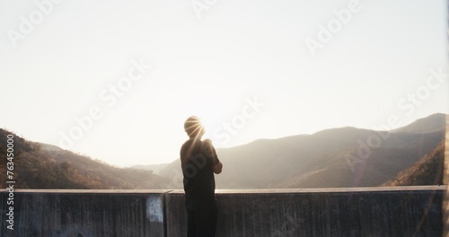 A man stands on a ledge looking out over a mountain range photo