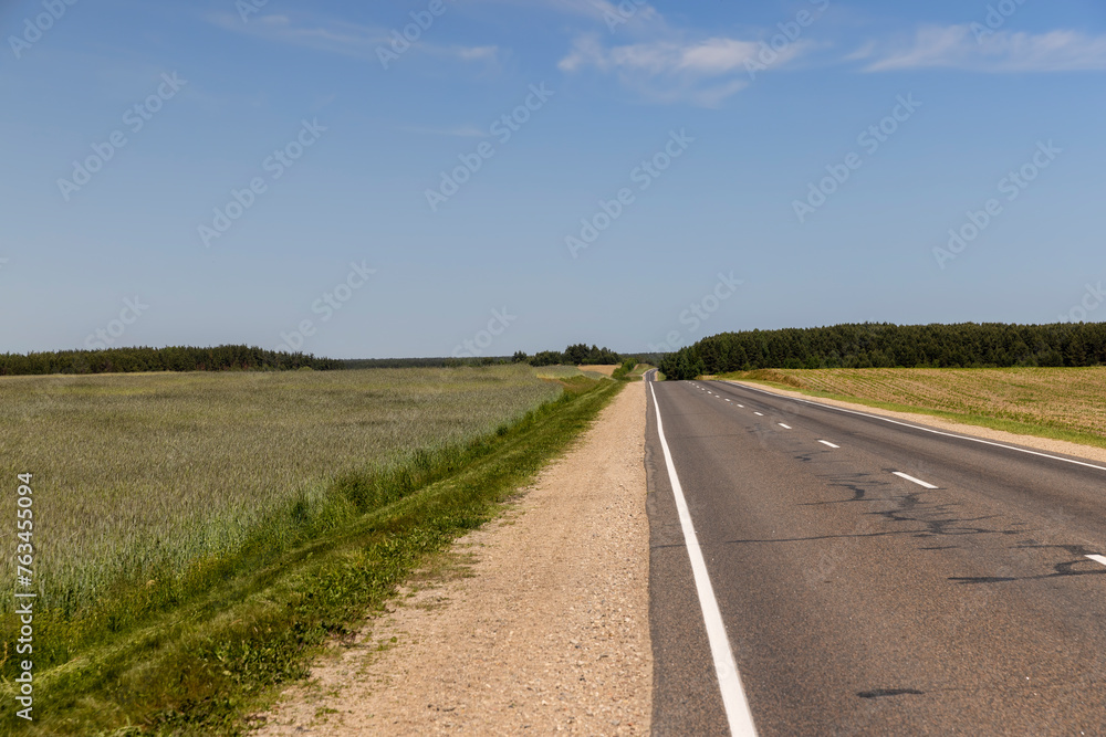 paved narrow road in a straight line through the field paved narrow road in a straight line through the field
