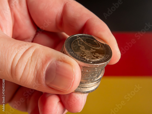 Hand Holding Euro Coins with German Flag Background