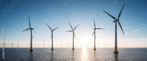 a row of wind turbines in the ocean with the sun setting behind them