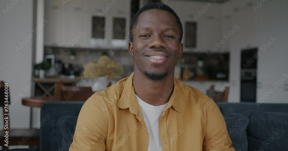 Slow motion portrait of cheerful African American guy smiling sitting in kitchen in modern apartment. Positive emotion and home concept. Slow motion portrait of cheerful African American guy smiling sitting in kitchen in modern apartment. Positive emotion and home concept.