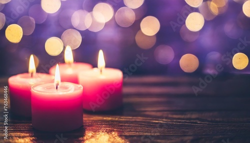 flaming pink aroma candles at night on blurred purple background with bokeh lights candles in church as catholic symbol abstract festive backdrop christmas eve banner with copy space