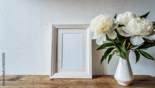 home interior with decor elements mockup with a white frame and white peonies in a vase on a white background © Richard