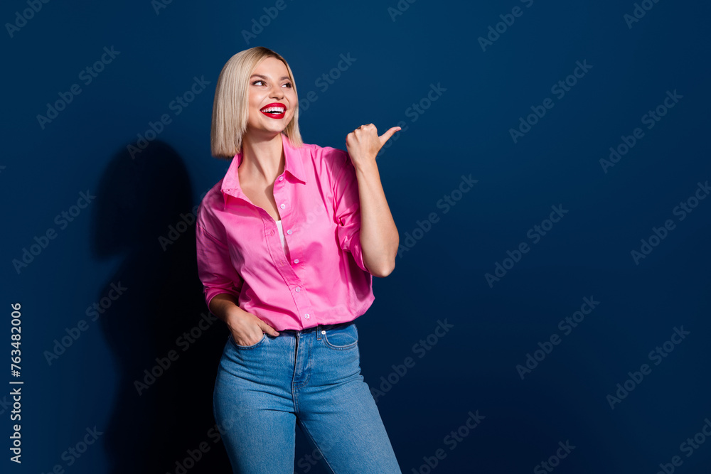 Fototapeta premium Photo of nice positive woman with bob hairstyle dressed pink shirt look directing at sale empty space isolated on dark blue background