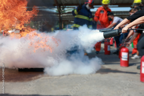 Employees firefighting training, Concept Employees hand using fire extinguisher fighting fire closeup. Spray fire extinguisher. 