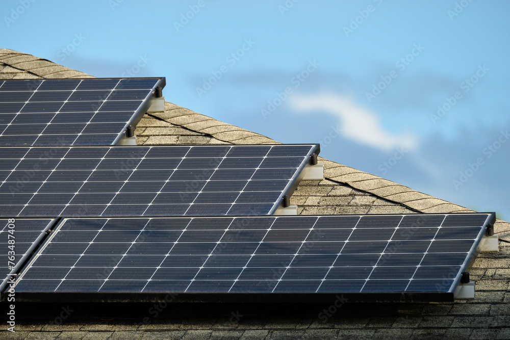 Fototapeta premium Residential house with rooftop covered with solar photovoltaic panels for producing of clean ecological electrical energy in suburban rural area. Concept of autonomous home