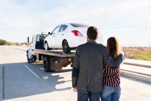 Man and young women hugging as they see their car being towed © felipe