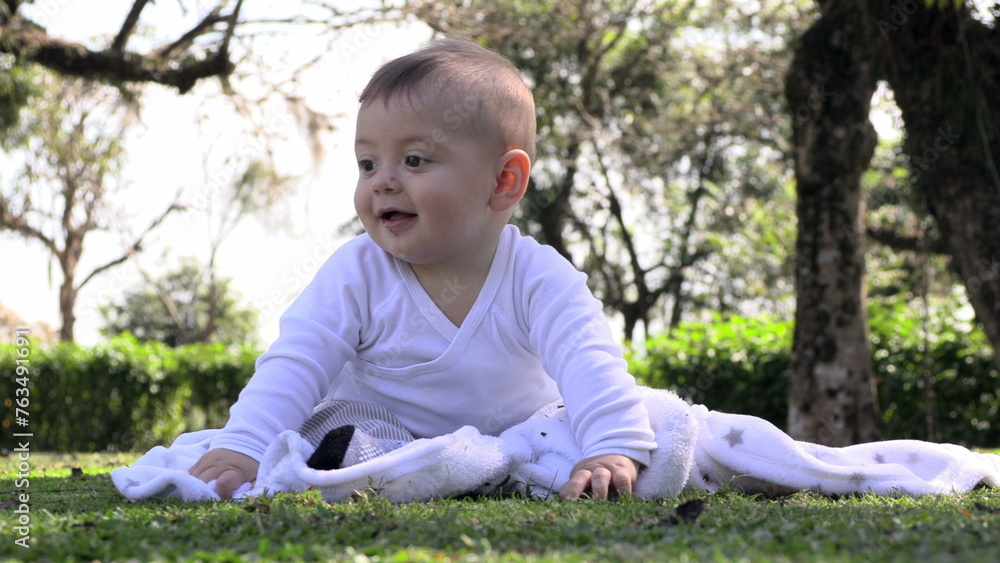 Happy small child baby boy feeling joy seated at outdoor park Happy small child baby boy feeling joy seated at outdoor park