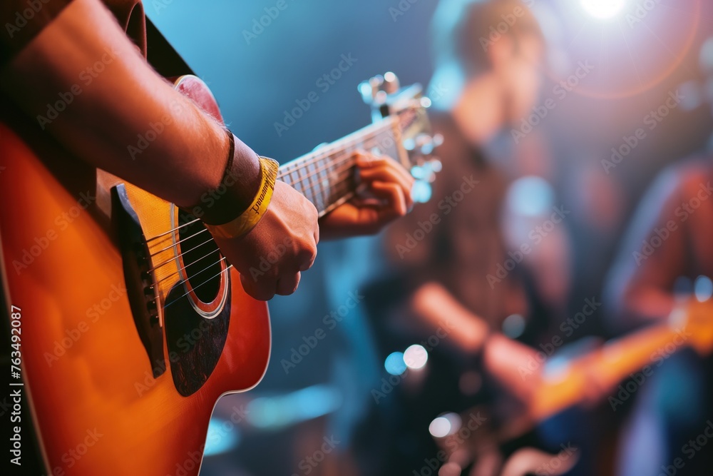 Naklejka premium Guitarist strumming an acoustic guitar on a lit stage, in a musical performance
