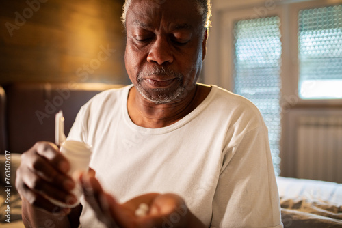 Senior man taking medication in bedroom