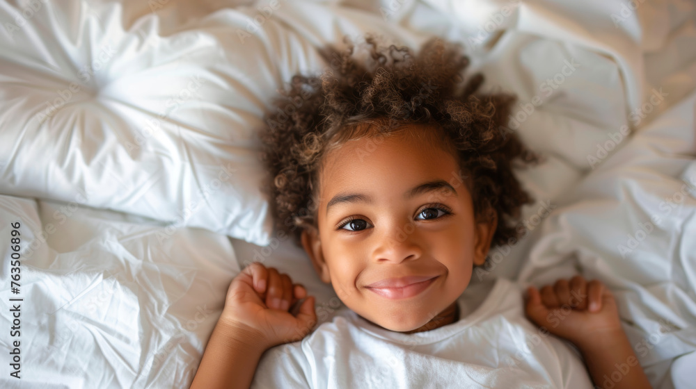 A smiling happy African American boy is lying on the bed in the bedroom. A smiling happy African American boy is lying on the bed in the bedroom.