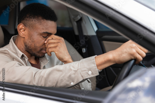 Young man sitting inside his car and feeling stressed and upset