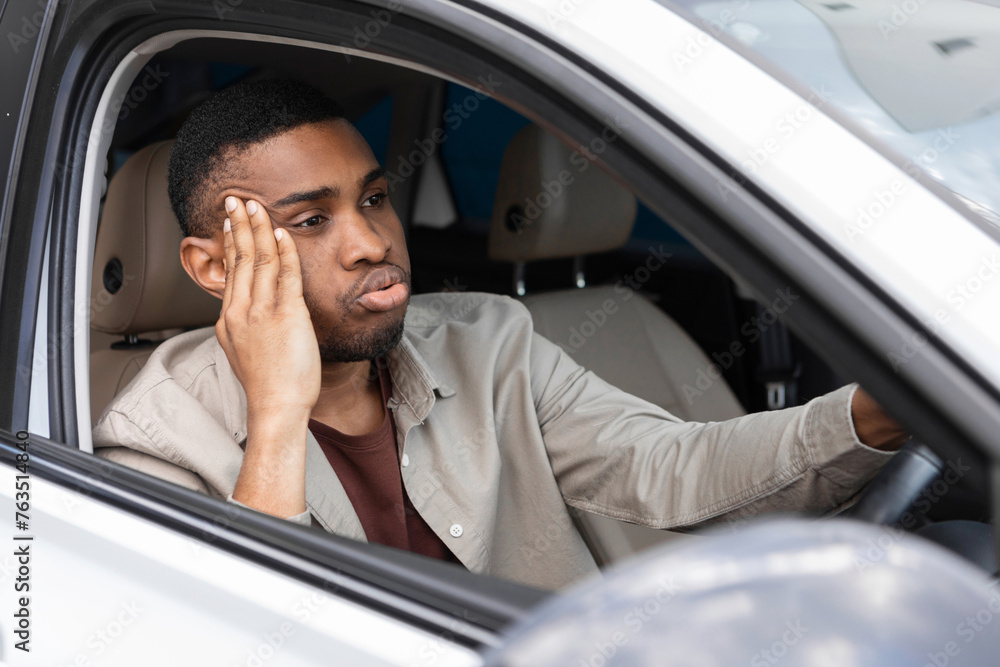 Stressed man sitting in the driver's seat of a car looks into the windshield Stressed man sitting in the driver's seat of a car looks into the windshield
