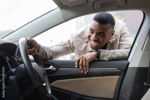 Black guy looks at the interior of the car, choosing a new car Selective Focus © Home-stock