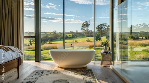  A modern bathroom featuring floor to ceiling windows that provide expansive views of a verdant setting and a standalone bathtub. © muhammad