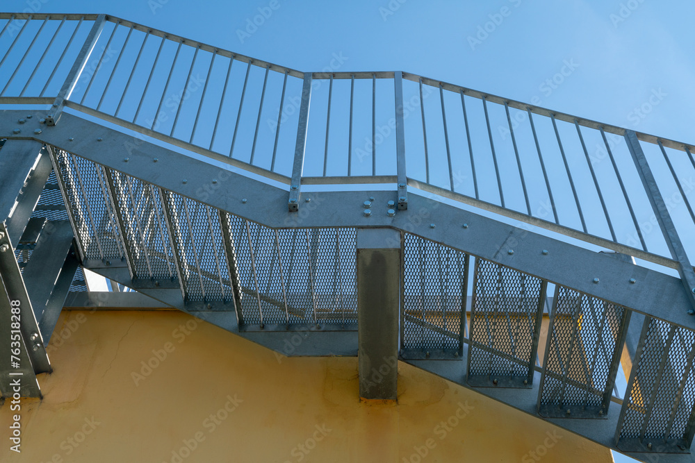 Fototapeta premium fire escape staircase, pedestrian passage for emergency exit. particular structure in galvanized stainless steel, with detail of the steel beams and their bolting.