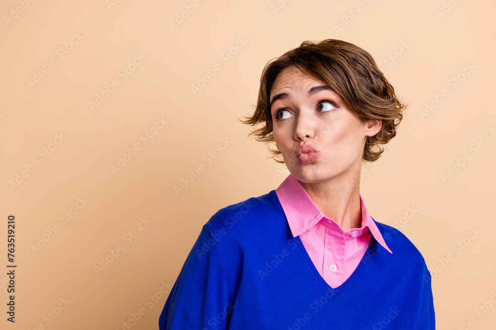 Photo portrait of lovely young lady look interested empty space pouted lips wear trendy blue garment isolated on beige color background Photo portrait of lovely young lady look interested empty space pouted lips wear trendy blue garment isolated on beige color background