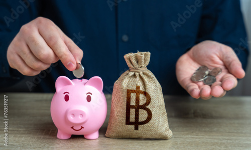Putting thai baht coins in a piggy bank. Accumulation of money. Banks and finance. Savings management. Investments, fundraising. Savings and accumulation of funds from cutting expenses. photo