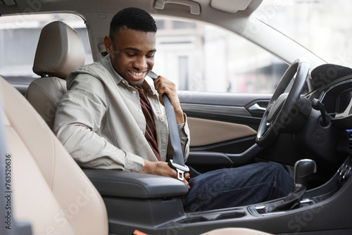 African American man sitting in a car in a car dealership fastening his seat belt photo