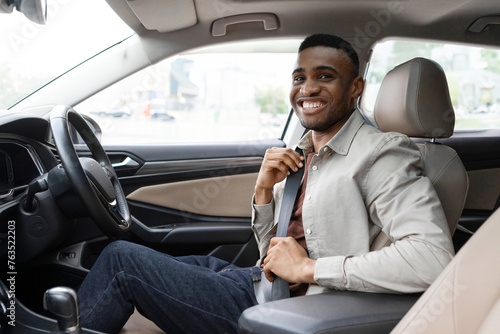 Portrait of a black man sitting in the driver's seat of a car and wearing a seat belt for safety