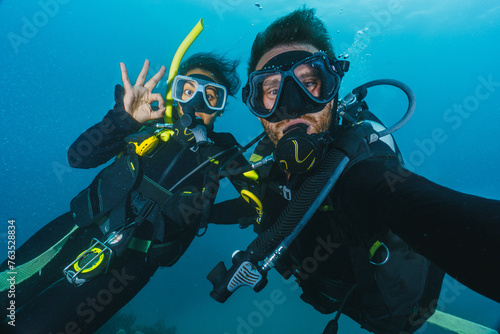 Two people are underwater, one of them is taking a selfie