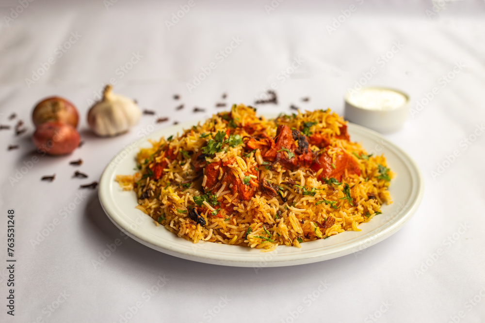 Mughlai Chicken tikka Biryani rice pulao with garlic, onion and raita served in plate isolated on background side view of indian and pakistani traditional food Mughlai Chicken tikka Biryani rice pulao with garlic, onion and raita served in plate isolated on background side view of indian and pakistani traditional food